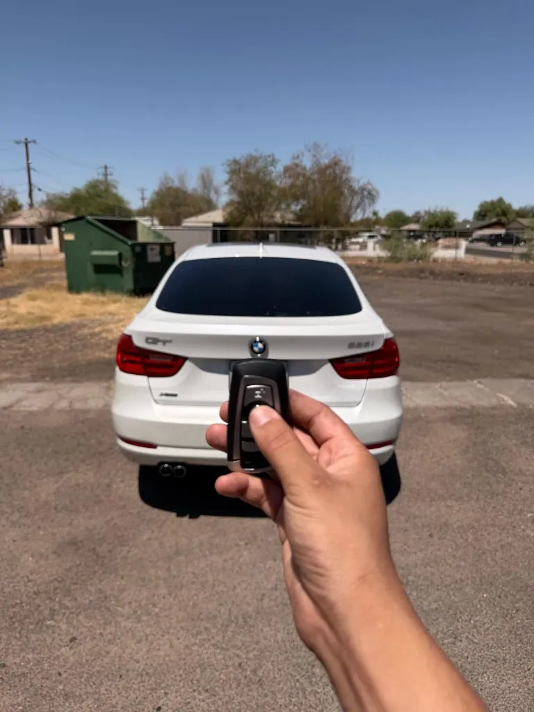 BMW remote key shown with the customer's white sedan after an all-keys-lost job